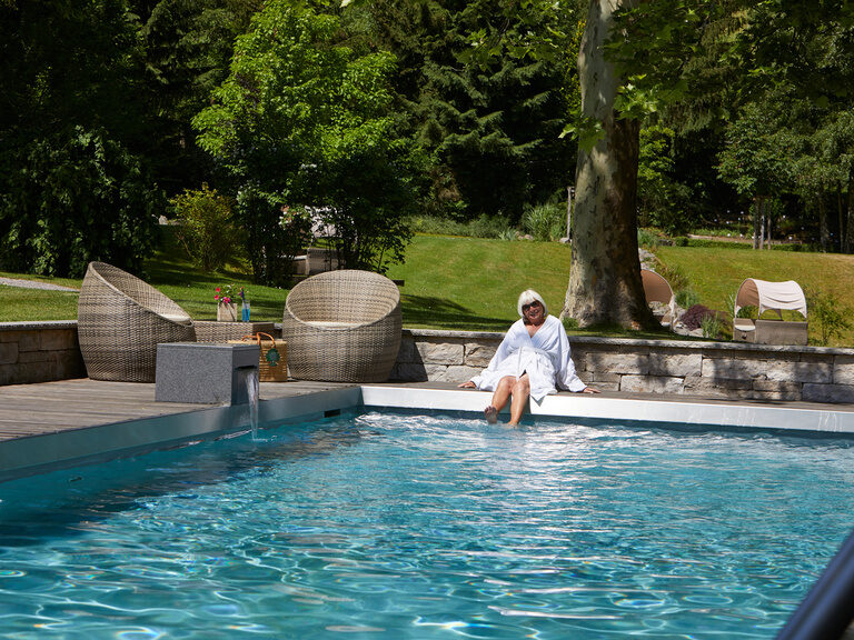 Ein Hotelgast relaxt im Poolbereich des Hotels bei Oberkirch, umgeben von naturnahem Ambiente.