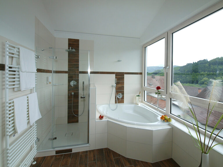 Eine ruhige Badezimmerlandschaft mit sichtbarer Badewanne und großem Fenster in der Panorama Suite des Waldhotels Grüner Baum.