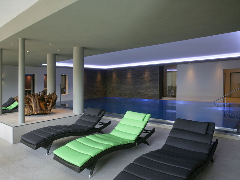 Die geschmackvollen Liegen im lichtdurchfluteten Poolbereich bieten den perfekten Entspannungsort im Waldhotel Grüner Baum im mittleren Schwarzwald.