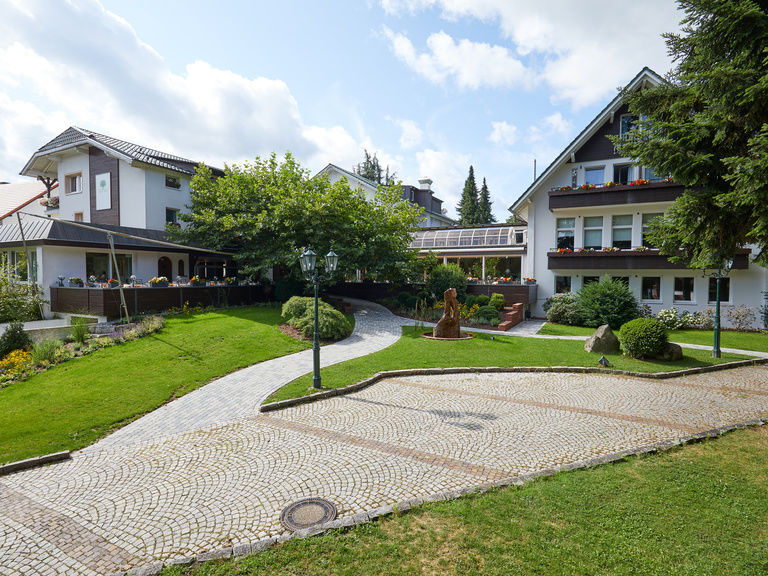 Die schöne Einfahrt zum Hotel Grüner Baum im Schwarzwald ist mit der gepflasterten Auffahrt und den Rasenflächen liebevoll gestaltet.