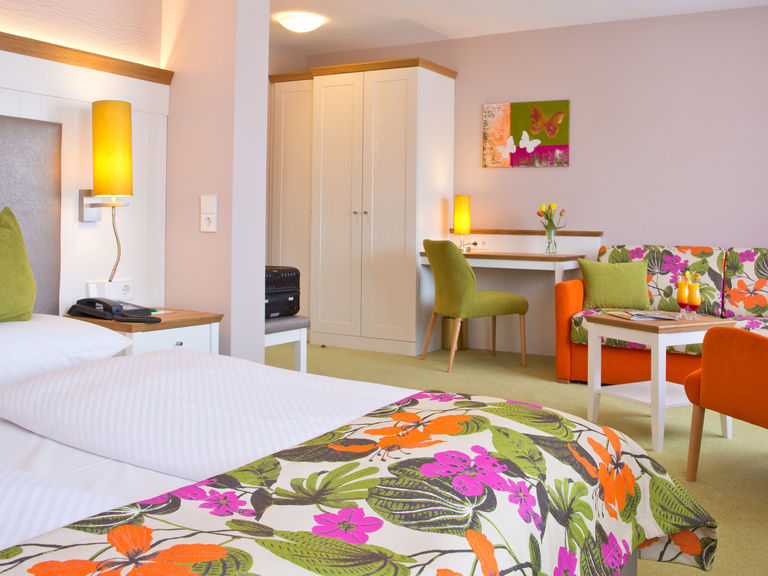 Das geschmackvoll eingerichtete Komfortzimmer wirkt durch die bunten Bezüge sehr lebhaft und gemütlich.