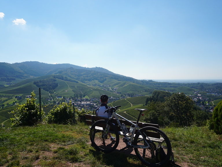 Ein Mann sitzt auf einem Hügel neben einem Fahrrad im mittleren Schwarzwald..