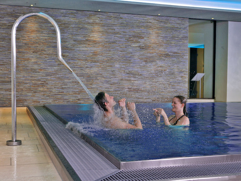 Im Wellnessbereich des Hotels genießen ein Mann und eine Frau das Baden.