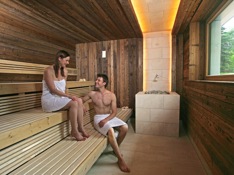 Ein Mann unterhält sich in der Sauna im Hotel im Schwarzwald mit einer Frau.
