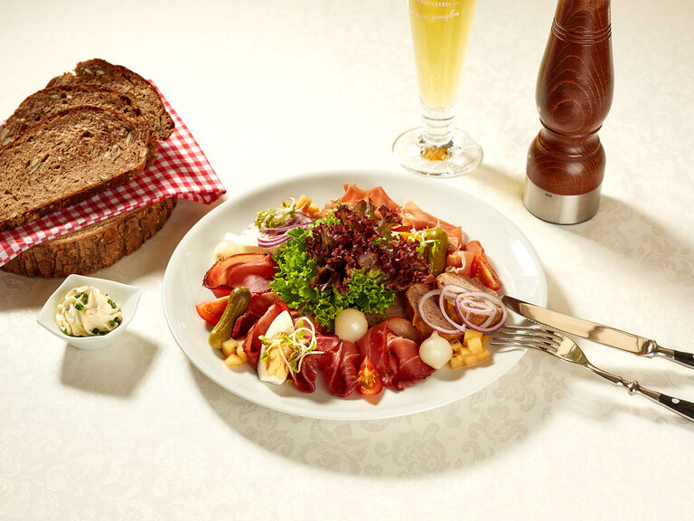 Ein elegantes Porzellanteller mit köstlichen Speisen neben einem Glas Bier.