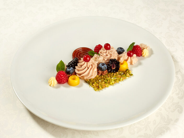 Ein weißer Teller mit Früchten und Nüssen im kreativen Kunststil angerichtet.