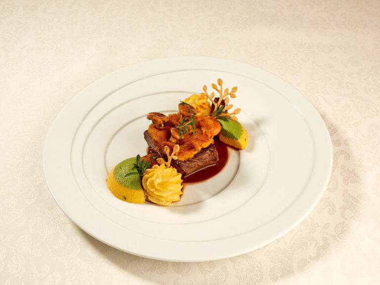 Ein eleganter weißer Teller präsentiert erlesene Speisen im Gartenambiente.