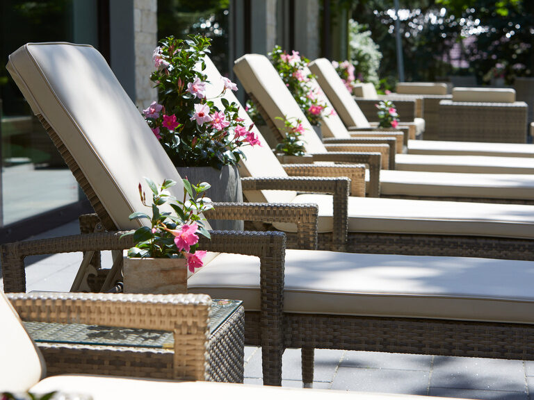 Ästhetisch angeordnete Outdoor-Möbel im Schatten am Außenpool des Waldhotels Grüner Baum.