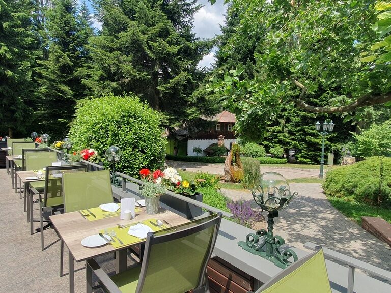 Ein gemütlicher Patio mit Tischen und Stühlen vor dem Haus des Hotels Grüner Baum..