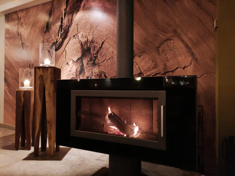 Ein moderner Kamin in einem gemütlichen Raum neben einem bequemen Sofa.