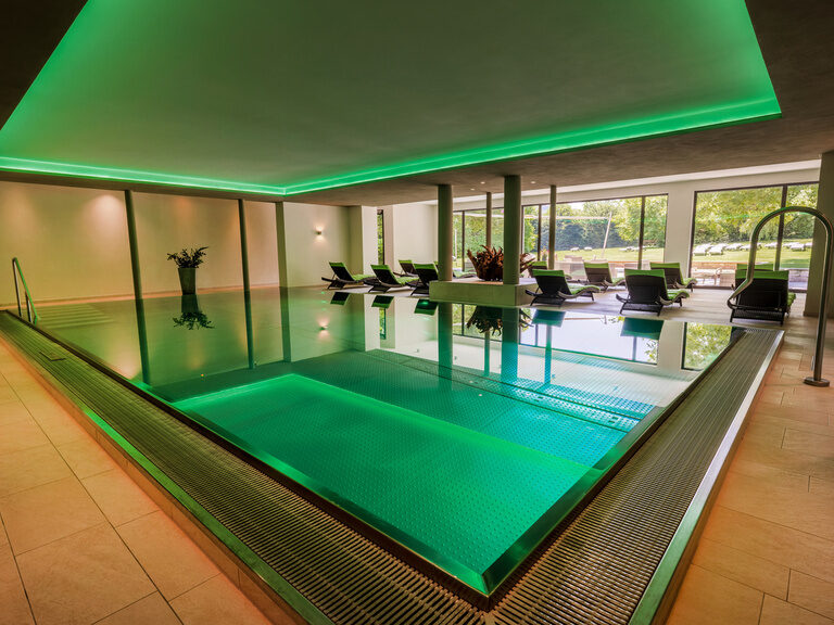 Ein eleganter Innenpool mit grüner Beleuchtung im Wellnessbereich des Hotels in Oberkirch.