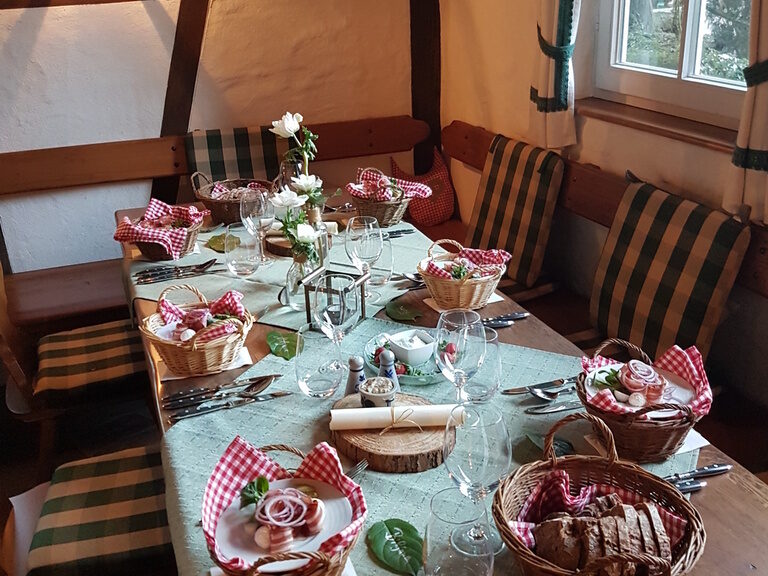 Ein Tisch im Brennhaus, elegant mit Tafelsilber und Tafelgeschirr für ein Dinner gedeckt.