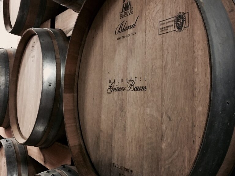 In einem Keller werden hochwertige Weinfässer in einem Regal an der Wand gelagert