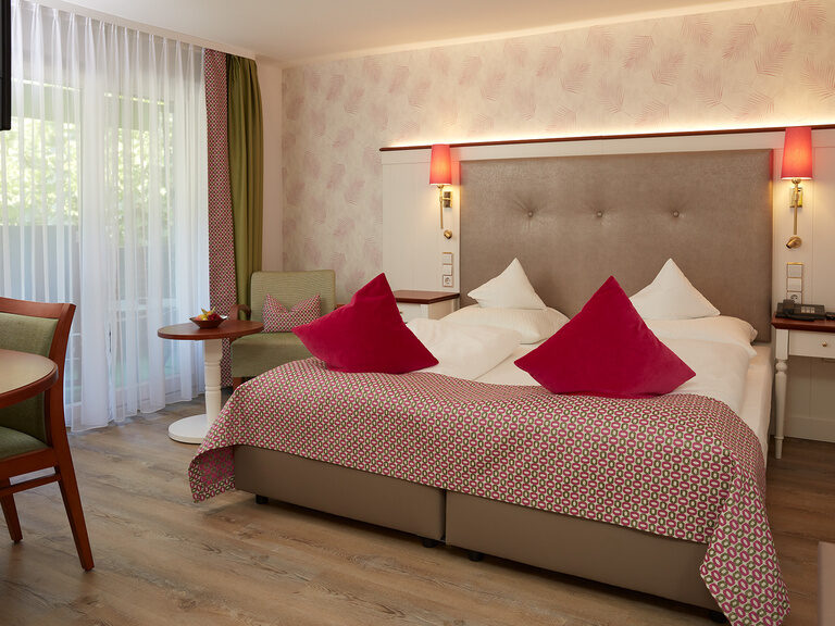 Ein gemütliches Komfortzimmer im Hotel mit großem Bett und eleganten Leuchten für den perfekten Wellnessurlaub.