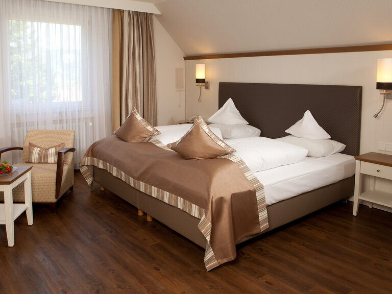 Ein komfortables Bett und Stühle im Komfortzimmer des Waldhotel Grüner Baum.