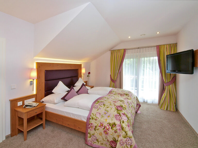 Die Panorama Suite ist schön aber schlicht mit einer Blumenbettwäsche und Vorhängen dekoriert und bietet unter anderem eine Flatscreen-TV.