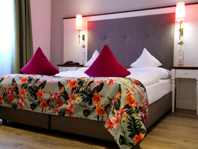 Ein elegantes Schlafzimmer im Hotel Grüner Baum mit sorgfältig platziertem Nachttisch.