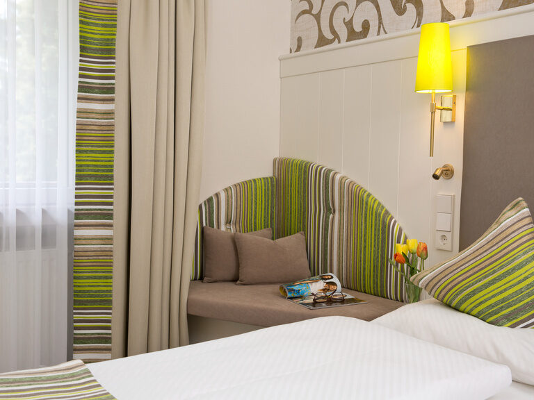 Ein stilvoll eingerichtetes Standartzimmer mit großem Bett und Fenster im Waldhotel Grüner Baum