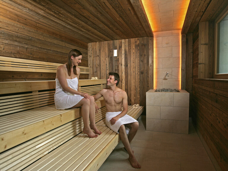 Ein Mann und eine Frau genießen einen Saunagang in der Panoramasauna ihrem Wellnessurlaub im Renchtal.