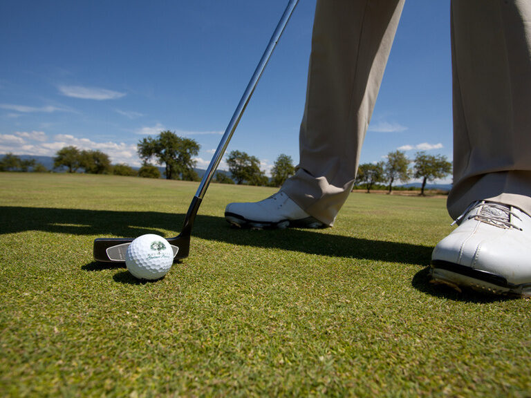Eine Person spielt einen Ball mit dem kleinen Putter und versucht dabei das Loch zu treffen