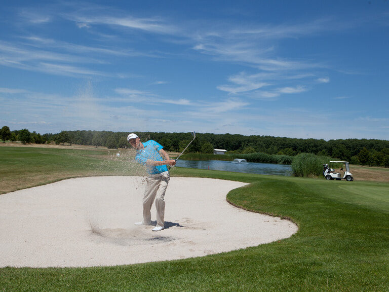 Ein Golfspieler spielt einen Ball aus einem Sandbunker.