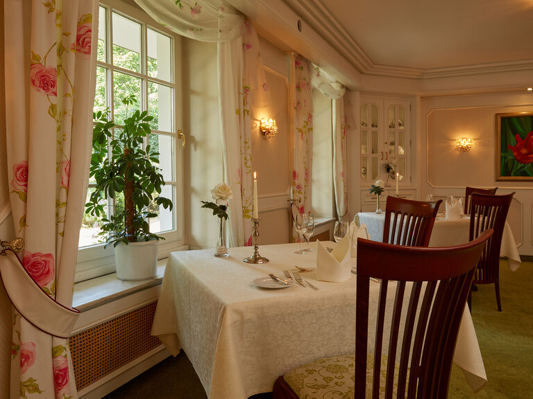 Ein eleganter Esstisch steht im Restaurant des Hotels, umgeben von stilvollen Stühlen.