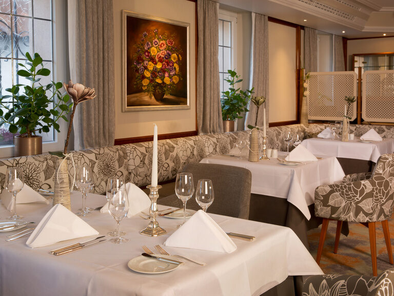 Eine festliche Tischdekoration mit weißem Tischtuch im Bankettsaal des Hotels