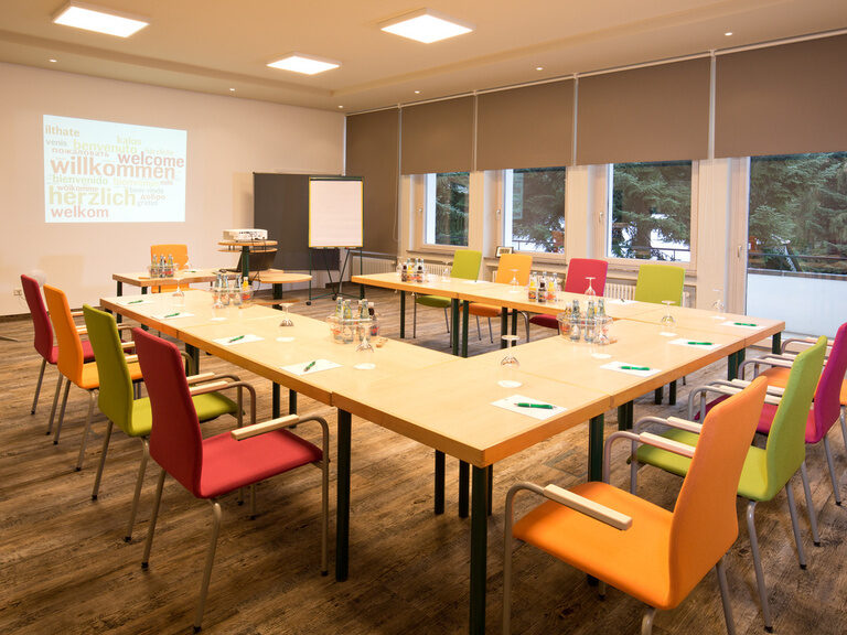 Mehrere Tische und Stühle in einem eleganten Konferenzraum mit moderner Beleuchtung im Hotel Grüner Baum im mittleren Schwarzwald.