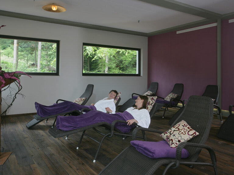 Ein Mann und eine Frau genießen zugedeckt auf Liegen ihren Wellnessurlaub.