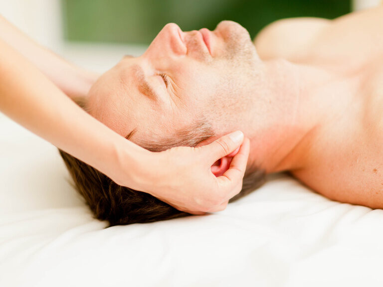 Ein Mann entspannt sich auf einem weißen Bett im Bereich der Wellness-Therapie.
