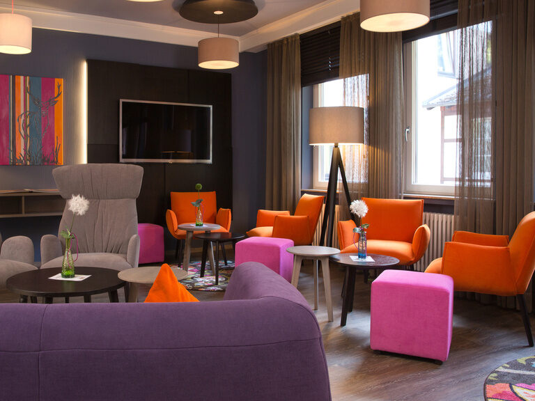 Das stilvoll eingerichtete Wellness-Wohnzimmer im Waldhotel Grüner Apfel wirkt durch seine bunten Möbel lebhaft und offen.