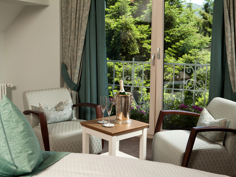 Ein stilvoll eingerichteter Wohnbereich mit Sesseln und Tisch im Deluxezimmer des Waldhotels Grüner Baum im mittleren Schwarzwald..