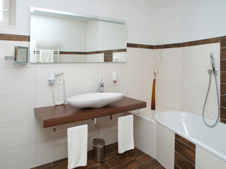 Ein elegantes Badezimmer mit Waschbecken, Spiegel und Badewanne im Wellnesshotel Grüner Baum im mittleren Schwarzwald.